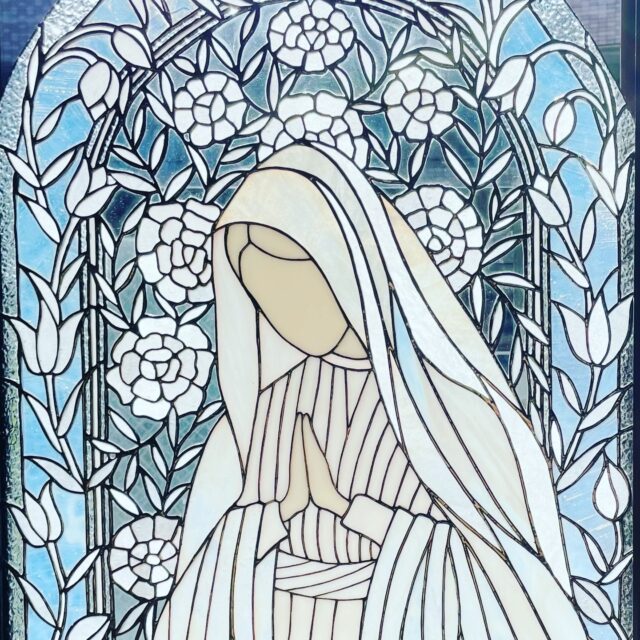 2024年5月12日～18日　東京都立美術館　「小さきものの祈り」
日本ステンドグラス作家協会 展示会出展作品

ひとりの小さな祈りの姿を、
白とクリアガラスの静かな光の中にそっと閉じ込めた作品です。

光の角度によって青く映るアーチや、
うすいピンクの花の色が変わるように、
透明感のある静かな祈りの世界を、
ガラスの質感とラインの流れで丁寧に演出しました。

手を合わせる小さな存在が、
静かに平和な世界を増やしていきますように。

そんな祈りの時間を、
花の世界に閉じ込めています。

#ステンドグラス #stainedglass #glassart
#祈りのアート #青の世界 #癒しのアート
#ガラス工芸 #ティファニー技法 #ステンドグラス作家
#アートのある生活 #静かな時間